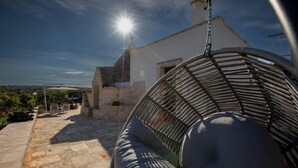 A stone patio with a hanging chair and a white building in the background. - Huge Villa With Private Pool in Salento, Italy (Ceglie Messapica)
