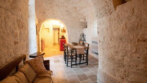 A narrow stone-walled corridor leading to a dining area with a wooden table and chairs. - Huge Villa With Private Pool in Salento, Italy (Ceglie Messapica)