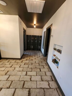 Um corredor com piso de tijolos, armários e uma parede branca com prateleiras.