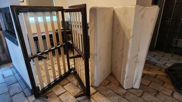 A room with a brick floor, a wooden gate, and two mattresses against the wall.
