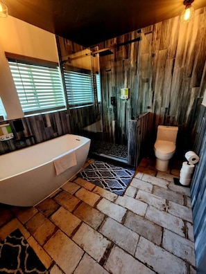 A bathroom with a bathtub, toilet, and shower area.