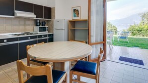 A compact kitchen with a dining area, a refrigerator, a microwave, and a stove. - Belvilla by OYO Gianni A Due Piao Due (Torri del Benaco)