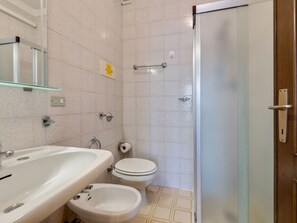 A bathroom with a sink, bidet, toilet, and a glass shower enclosure.