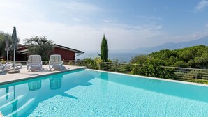 A swimming pool with lounge chairs and a view of the sea and mountains. - Belvilla by OYO Gianni A Due Piao Due (Torri del Benaco)