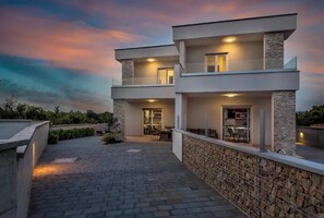 Stylish two-story building with a flat roof and symmetrical design, featuring a covered outdoor area with seating and a walkway.