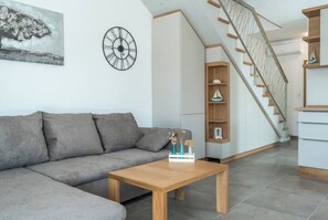 Relax in this stylish living space with a sofa, coffee table, and staircase leading to an upper level.