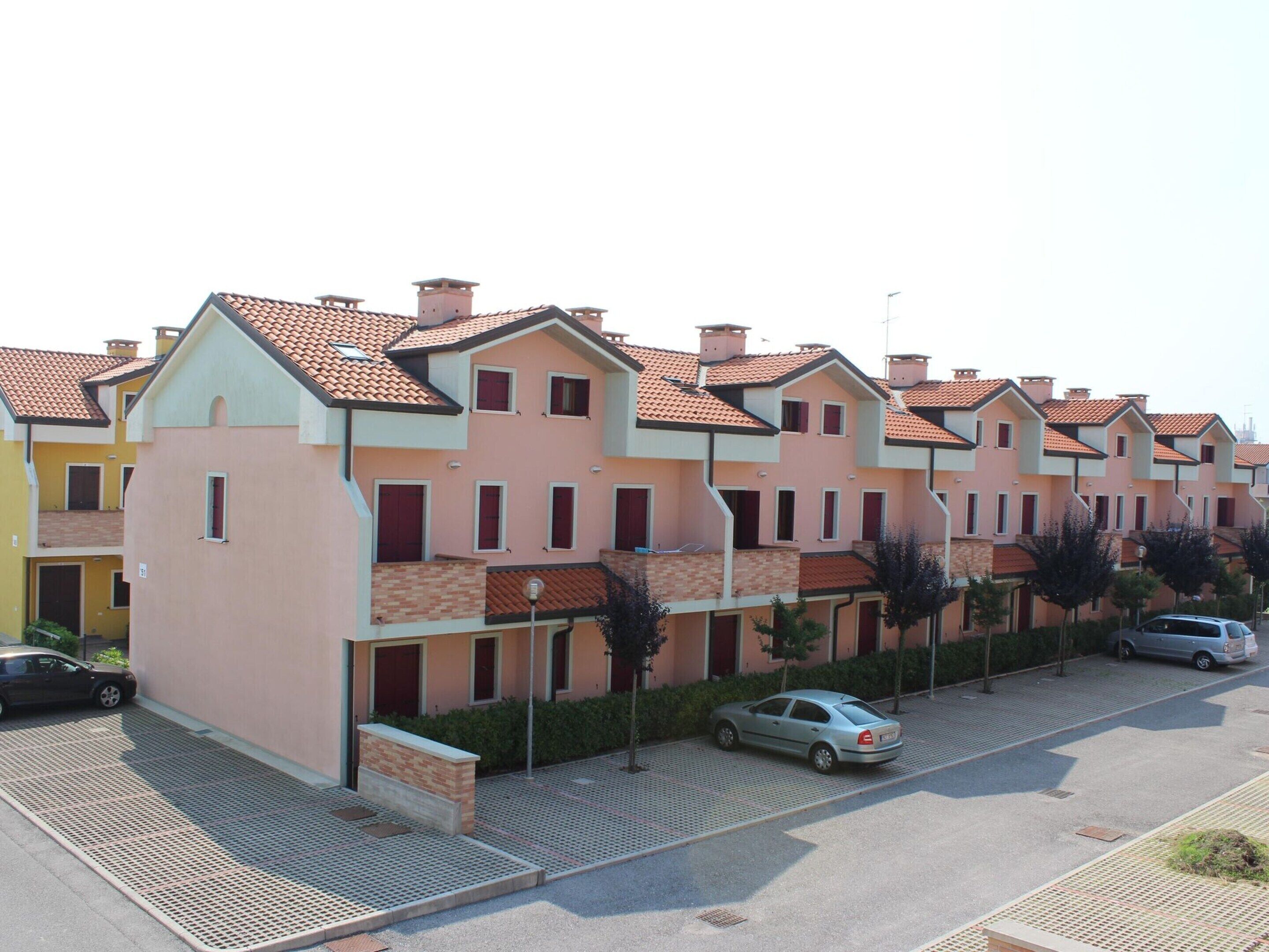 Fila de edificios residenciales de varios pisos con arquitectura uniforme, balcones y tejado de tejas.