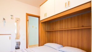 Un dormitorio con cama, armario y espejo.