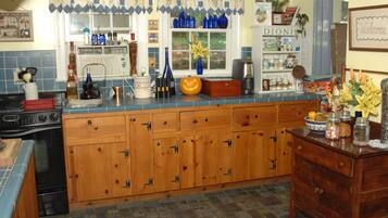 Una cocina con armarios de madera, estufa y ventana con cortinas azules.