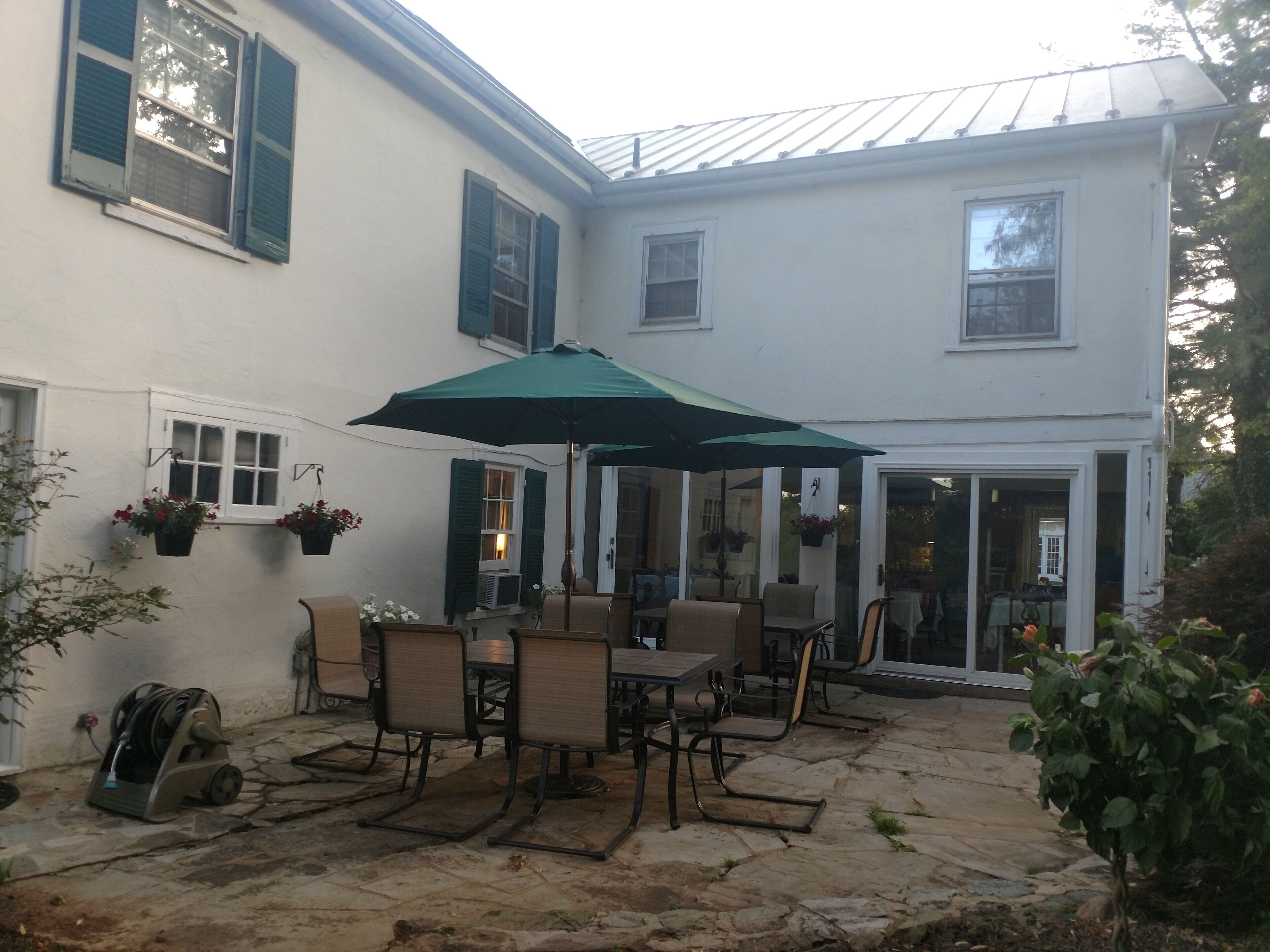 A patio with outdoor furniture and a green umbrella.