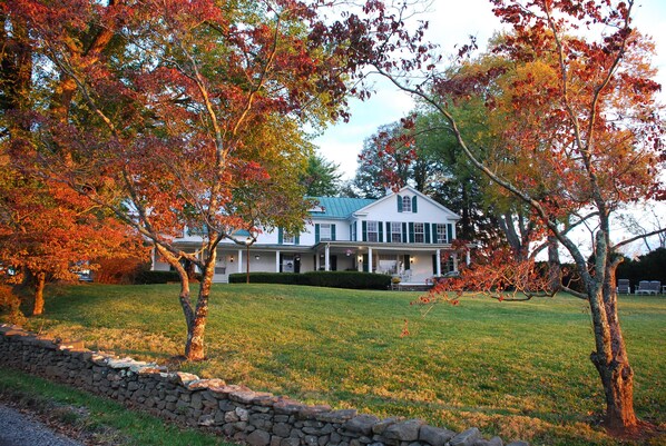 A large, two-story house with a well-maintained lawn and a stone wall in the foreground. - Briar Patch Bed & Breakfast Inn (Middleburg)