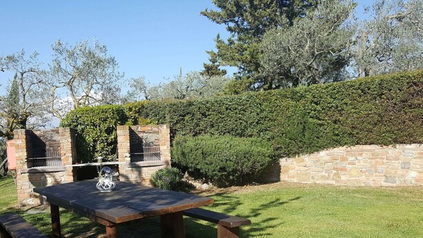 An outdoor patio with a stone barbecue grill, a wooden table, and benches. - Farmhouse in Castelfiorentino With Pool (Castelfiorentino)