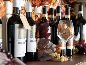 Varias botellas de vino y una copa con tapones sobre una mesa, rodeado de hojas otoñales y uvas.