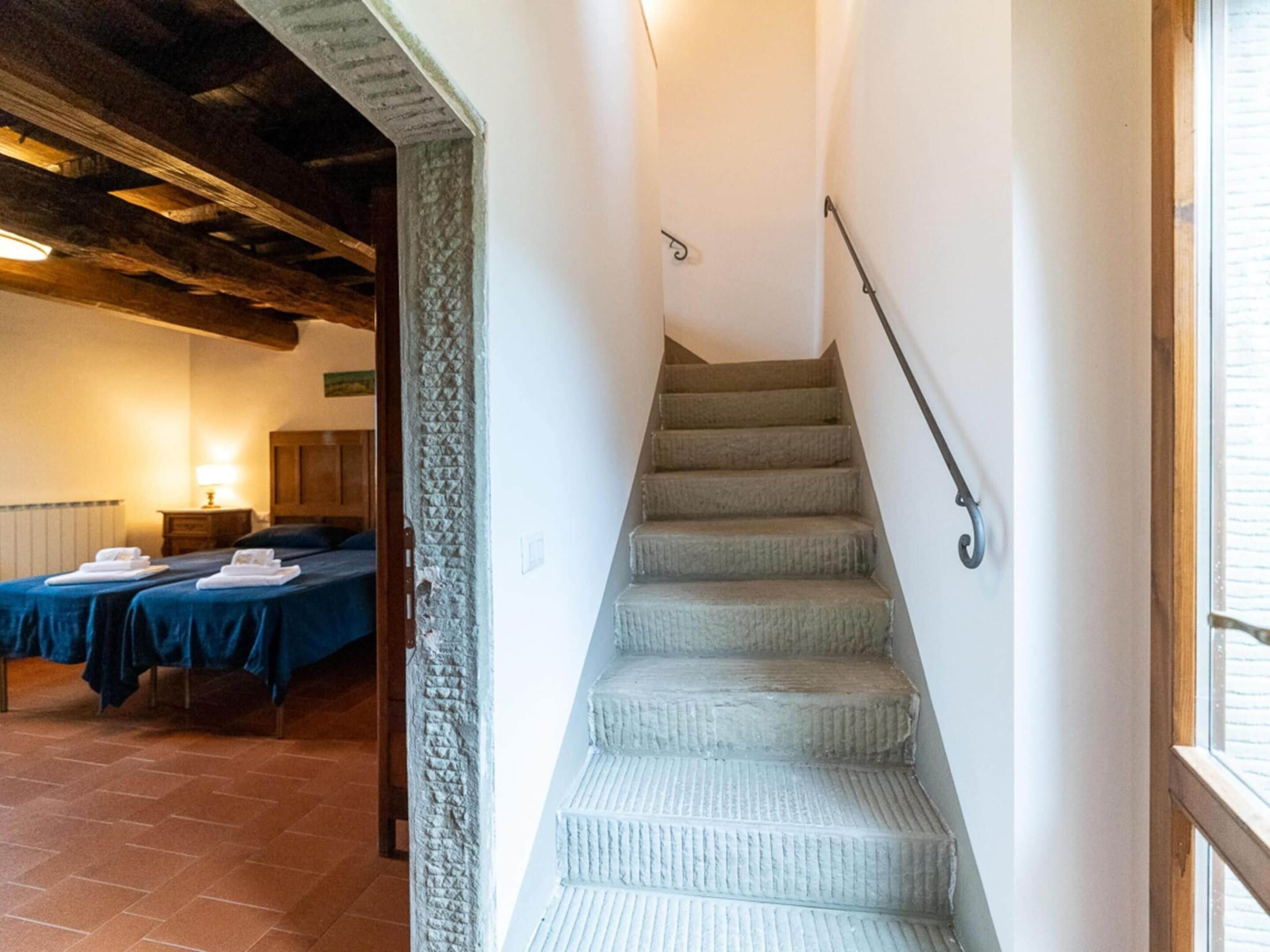 Una escalera con barandilla que lleva a una habitación con dos camas y una mesita de noche.