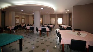 Un salón de conferencias con mesas y sillas, un pilar grande e iluminación empotrada en el techo.