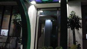 Entrada de edificio con un logotipo circular destacado que presenta una 'X' roja y una 'O' verde.