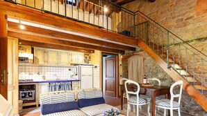 Ein gemütlicher Wohnbereich mit einer Couch, Sesseln, einem Tisch und einer Küche im Hintergrund.