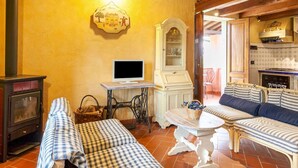 Ein gemütliches Wohnzimmer mit Kamin, Fernseher, Esstisch und einer Couch.
