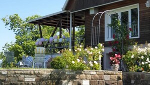 A two-story wooden house with a stone wall in front, a covered patio, and a balcony with a railing. - Chalet in Marliana Near Center (Marliana)