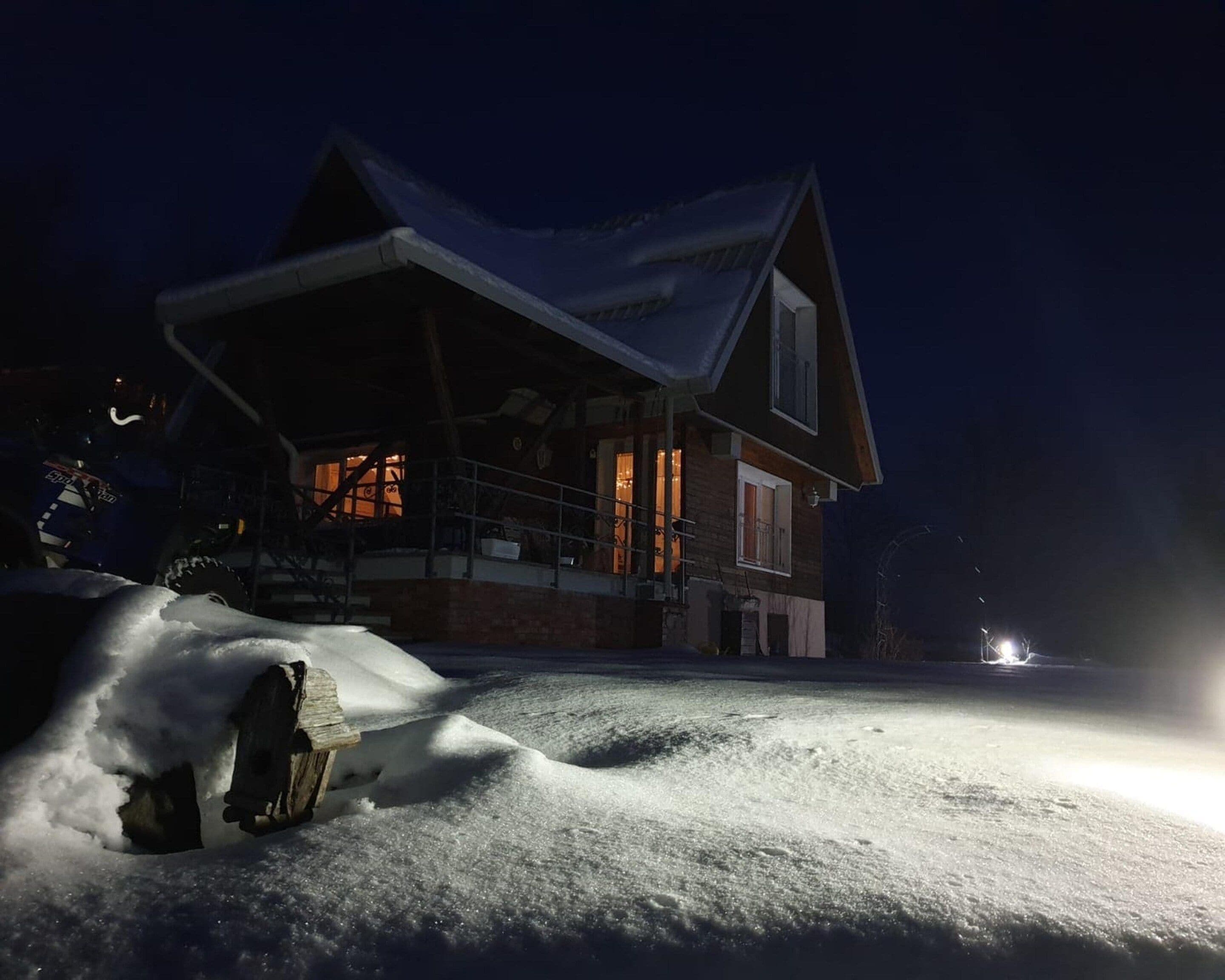 A house with a sloped roof and a covered porch, surrounded by snow.