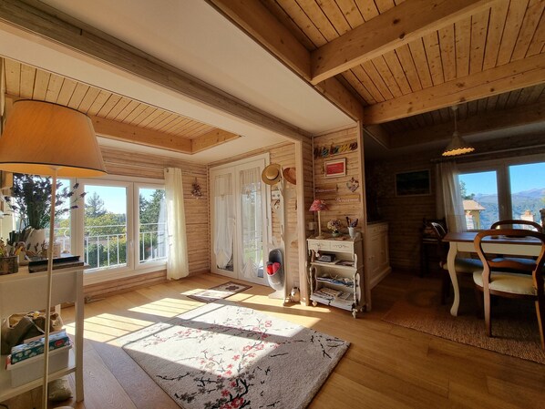 A cozy room with wooden beams, a large window, a wooden table, and a chair. - Chalet in Marliana Near Center (Marliana)
