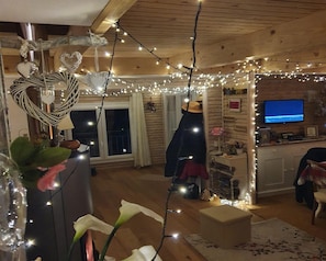A cozy living room with a wooden ceiling, string lights, a television, and a fireplace. - Chalet in Marliana Near Center (Marliana)