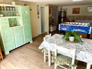 A dining area with a table set for four, a green cabinet with kitchenware, and a foosball table. - Chalet in Marliana Near Center (Marliana)