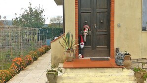 Une maison avec une porte en bois sombre, un petit porche décoré avec un motif du Père Noël et des plantes en pot.