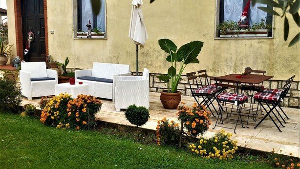 Un espace extérieur aménagé avec des meubles en osier blanc, une plante en pot et une table entourée de chaises.