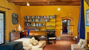 Ein gemütliches Wohnzimmer mit einer Couch, Sesseln und einem Bücherregal voller Bücher.