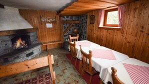 Une pièce rustique avec des murs en bois, une cheminée en pierre, des tables et des chaises en bois.