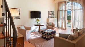 A spacious living room with a high ceiling, a fireplace, a television, and a large window with curtains. - Belvilla by OYO Villa Terra (Reggello)