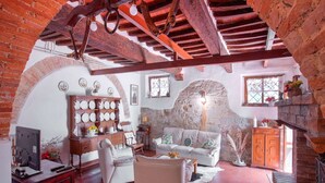 Una sala de estar acogedora con chimenea, un sofá blanco y un mueble de madera.