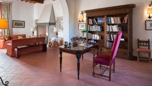 A cozy living room with a fireplace, a wooden bookshelf, a red armchair, and a coffee table. - Belvilla by OYO Villa Iole (Reggello)
