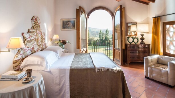 A bedroom with a bed, bedside table, lamp, and a view of the outdoors. - Belvilla by OYO Villa Iole (Reggello)