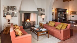 A cozy living room with a fireplace, a sofa, a coffee table, and a bookshelf. - Belvilla by OYO Villa Iole (Reggello)