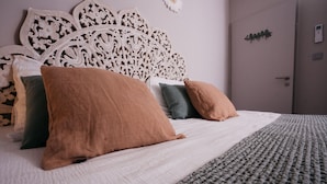 A neatly made bed with a white duvet and several pillows, a textured grey blanket, and a decorative headboard. - MAS SAINT LAURENT (Les Salles-du-Gardon)