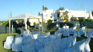 De longues rangées de chaises blanches, recouvertes de nappes, ont été installées à l’extérieur, probablement pour un événement.