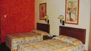 Une chambre d’hôtel avec deux lits, un mur rouge et deux lampes fixées au mur.
