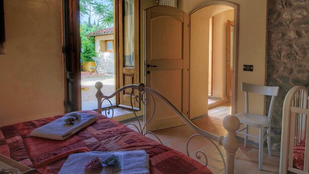 Un dormitorio con cama, una silla, un armario y una puerta que da a un balcón.