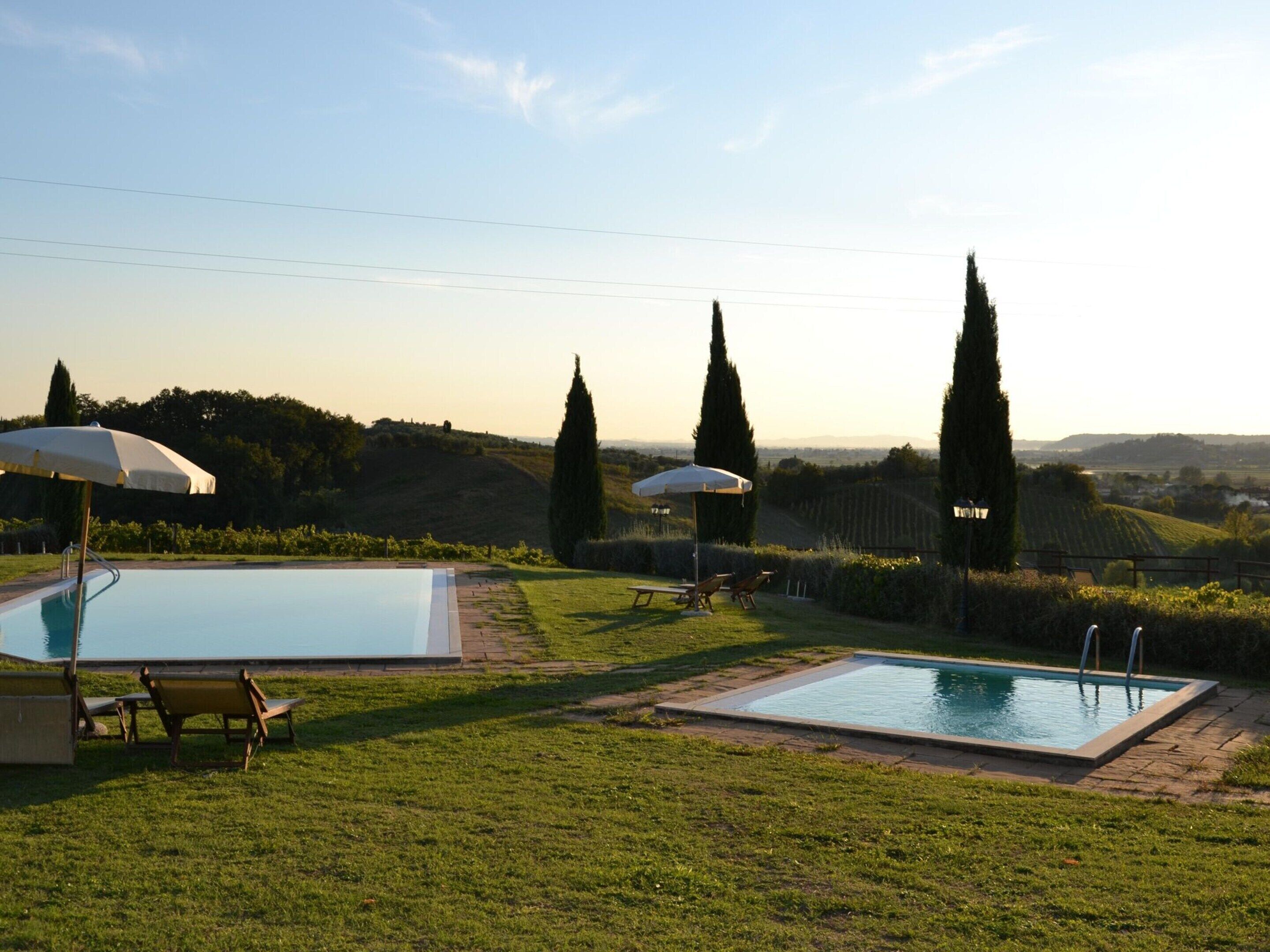 A pool area with two pools, lounge chairs, and umbrellas.