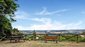 A picnic area with a bench and table, surrounded by a wooden fence with a view of rolling hills. - Elegant Escape in Tuscan (Gambassi Terme)