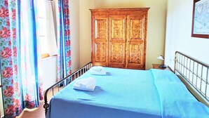 A bedroom with a bed, a wooden wardrobe, a map on the wall, and floral curtains. - Elegant Escape in Tuscan (Gambassi Terme)