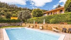 Una piscina rettangolare con acqua cristallina, circondata da pareti in pietra e una scala in pietra che conduce a un edificio.