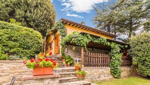 Una casa in pietra con un portico in legno, piante in vaso e una scala in pietra che conduce all'ingresso.