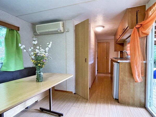 A compact kitchenette with a sink, a small refrigerator, and a window with curtains.