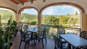 A terrace with outdoor seating, brick arches, and a view of a hilly landscape. - Scenic Retreat, Pergine Valdarno (Pergine Valdarno)