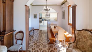 A spacious room with a long wooden table and benches, a patterned floor, and a view into a kitchen area. - Scenic Retreat, Pergine Valdarno (Pergine Valdarno)