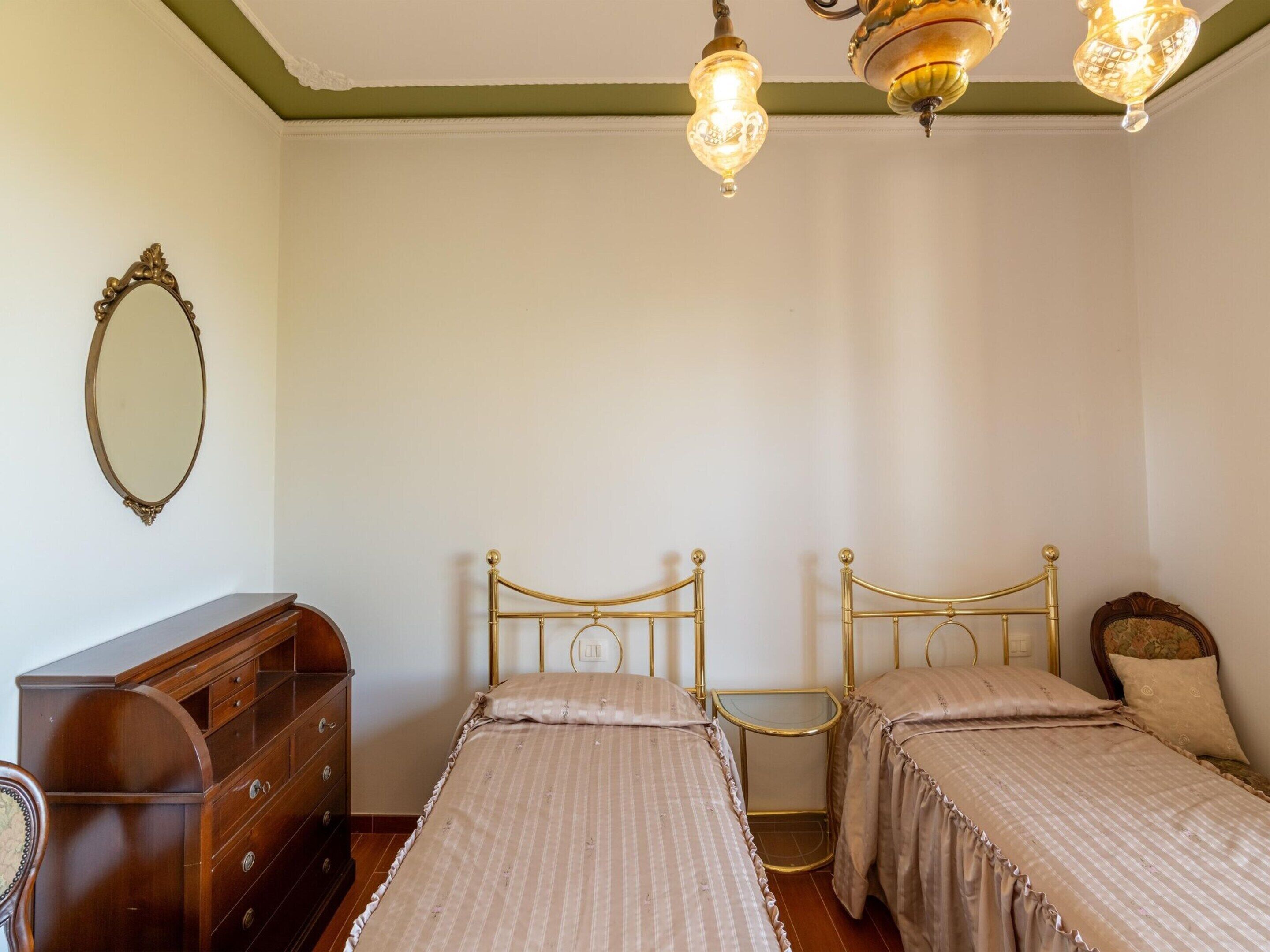 A room with two single beds, a wooden dresser, a mirror, and a small table.