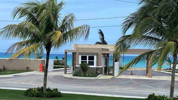 Een modern gebouw met een glazen entree, omgeven door palmbomen en uitzicht op de oceaan.